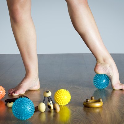 ballet dancer massaging her foot with blue ball for massage