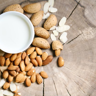 Almond and almond milk on a wooden table in the summer garden. Useful food