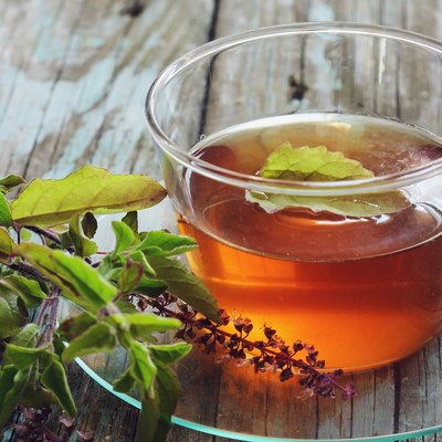 Tulsi Tea served in a cup with fresh leaves on the side, selective focus