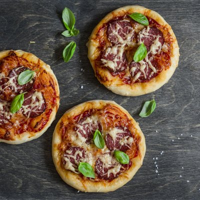 Mini salami pizza on a dark wooden background, top view