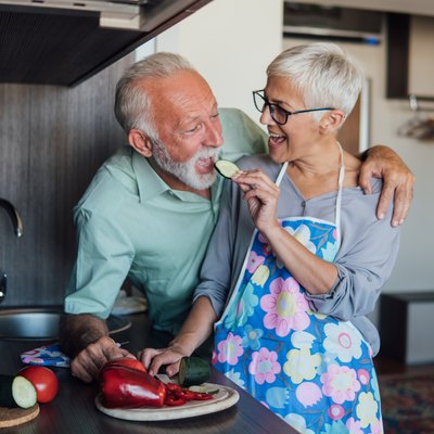 senior woman feeding senior man a slice of cucumber