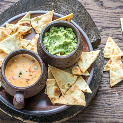 Bowls of guacamole and queso with tortilla chips.