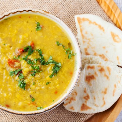 Toor dal with pita bread in a ceramic white bowl on a wooden background. Top view. Copy space