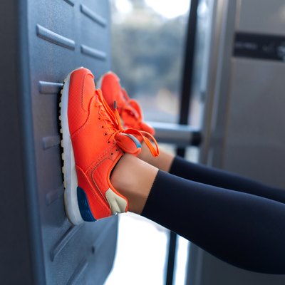 Slim smiling woman using a leg press machine and placing her legs on the platform