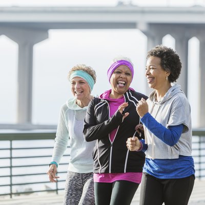Three mature women power walking together on waterfront