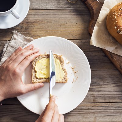 Woman hand spreading vegan butter on sliced bread