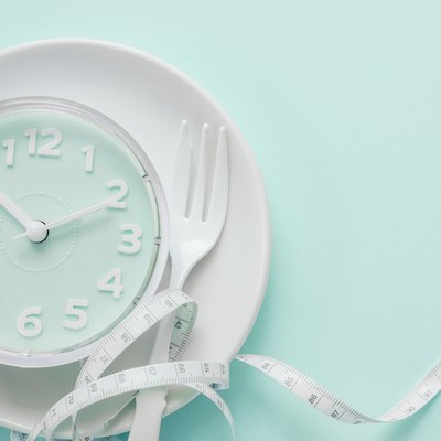 Blue clock on white plate, Intermittent fasting concept, ketogenic diet, weight loss, skip meal
