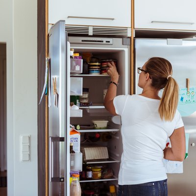 woman storing canned food in fridge