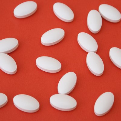White oval IP 466 ibuprofen pills on a red background