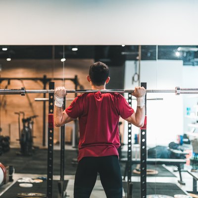 rear view of man using barbell to do a good morning exercise