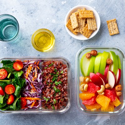 Lunch box with vegetables, brown rice and fruits salad. Healthy eating. Grey background. Top view.