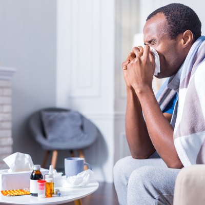 Adult man sneezing because he has the flu