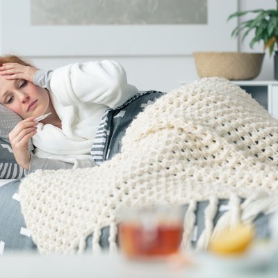 Ill woman looking at thermometer