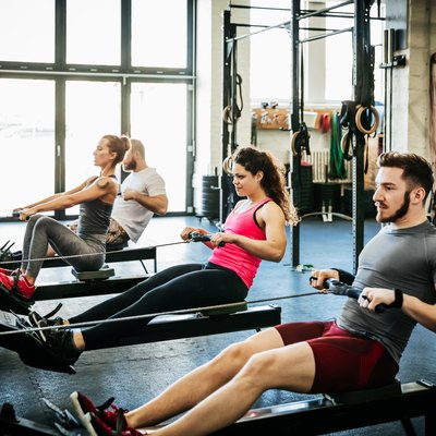 Fitness Enthusiasts Exercising Using Rowing Machines