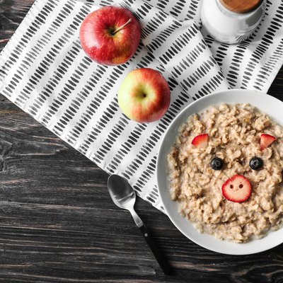 Plate with creative oatmeal for children on dark wooden table