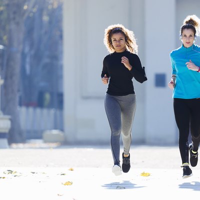 Two focused young women running listening to music