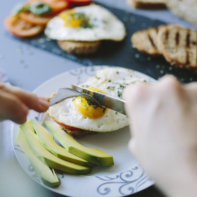 Breakfast with eggs, avocado, bread and tomatoes for healthy fats
