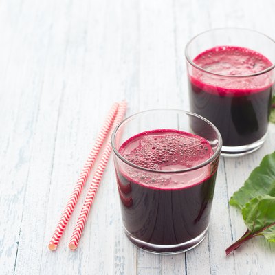 Fresh beet juice in glasses with a straw on a light blue background