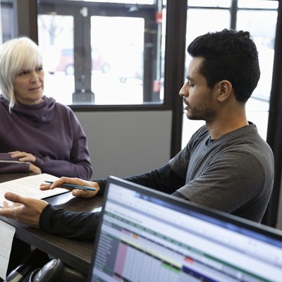 Personal trainer talking with senior woman at gym