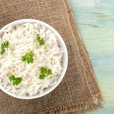 A photo of a bowl of cooked white long rice, shot from the top on rustic textures with copy space