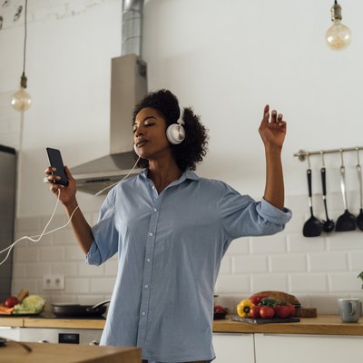 Woman dancing and listening music in the morning in her kitchen