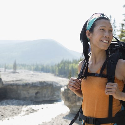 Woman backpacking above river, going on a long-distance walk