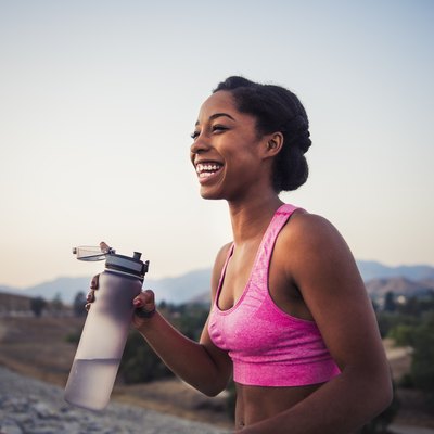 Happy female runner holding water bottle, preparing for her 5k training plan for beginners
