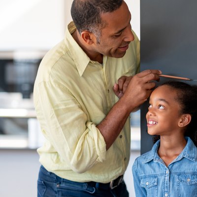 Father measuring his daughter against the wall