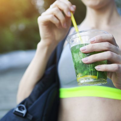 Woman drinking herbal tisane after fitness running workout on summer day