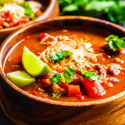 Traditional mexican bean soup with meat and cheese in wooden bowl, dark background