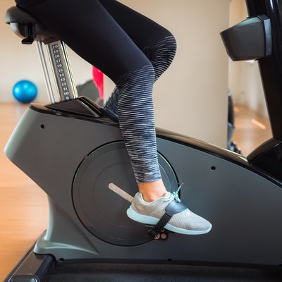 Low Section Of Woman Cycling On Exercise Bike In Gym