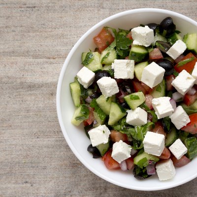Homemade Shepards salad with cucumbers, feta and parsley in a white bowl, top view. From above, overhead. Space for text.
