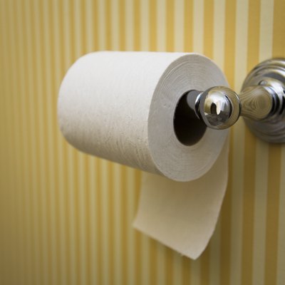 Toilet paper roll hanging in a bathroom with striped yellow wallpaper