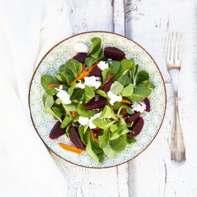 Plate of corn salad with roasted carrots, beetroots, red onions andgoat cream cheese