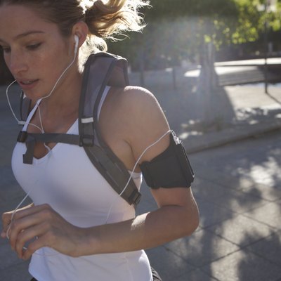Woman jogging outdoors with backpack and earphones, close-up