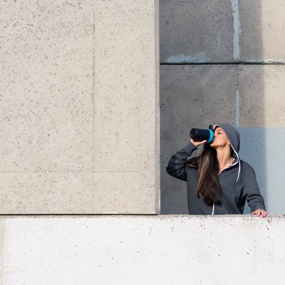 Fitness woman drinking protein shake after urban workout