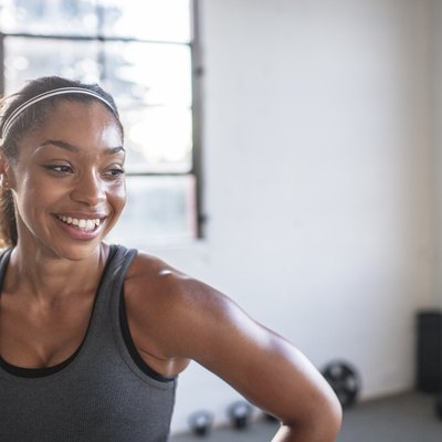 Close-up of smiling athlete looking away while standing in gym