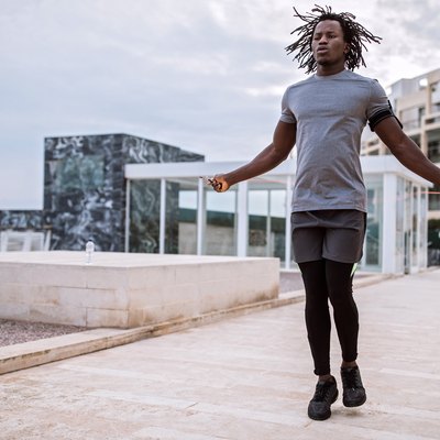 Athletic man performing double unders with a jump rope outdoors.