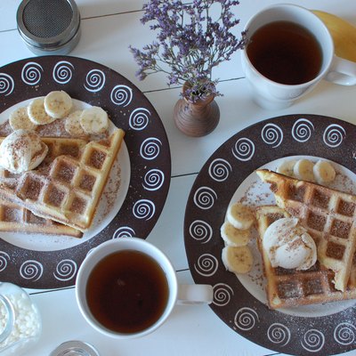 two white ceramic mugs beside plate of belgian waffles