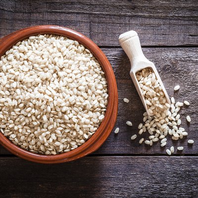 Brown bowl filled with brown rice shot from above on rustic wooden table