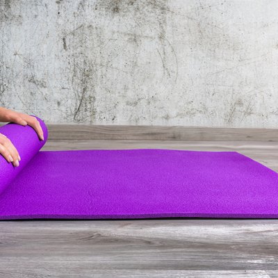 Low Section Of Person Rolling Yoga Mat
