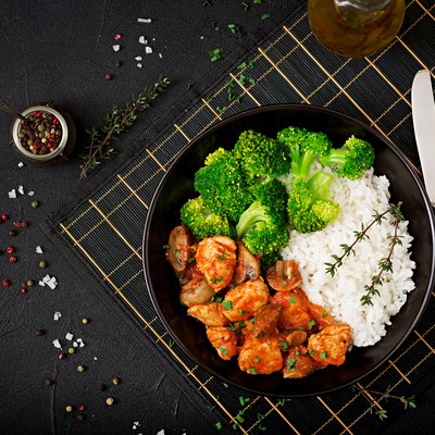 Pieces of chicken fillet with mushrooms stewed in tomato sauce with boiled broccoli and rice. Proper nutrition. Healthy lifestyle. Dietetic menu. Top view