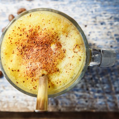 Golden milk latte with turmeric in a glass strewed with cinnamon, on a blue wooden background