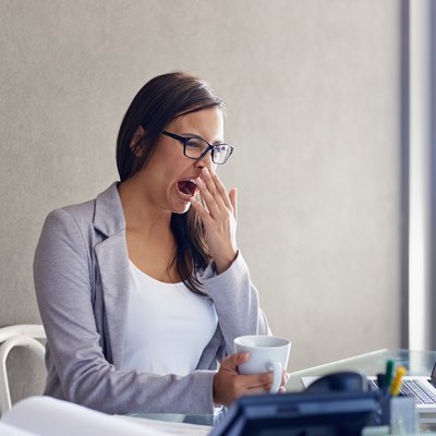 A woman yawning at her desk at work