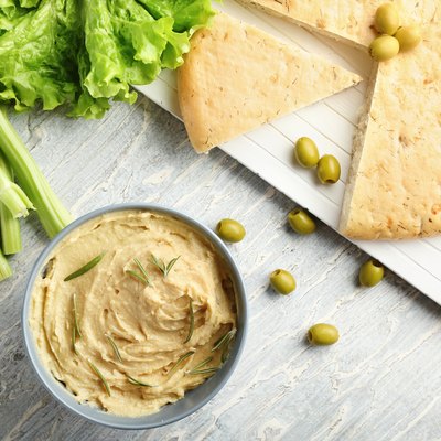 Bowl with tasty hummus, pita bread and olives on table