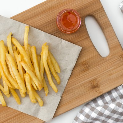 French fried potatoes on cutting board with sauce top view.