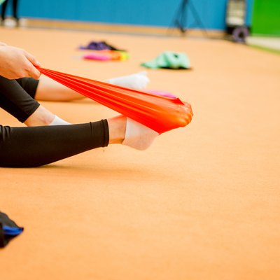 Young Rhythmic Gymnastics Athlete Stretching Legs with Resistance Band