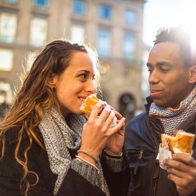 Young couple eating bread outdoors for carb diet