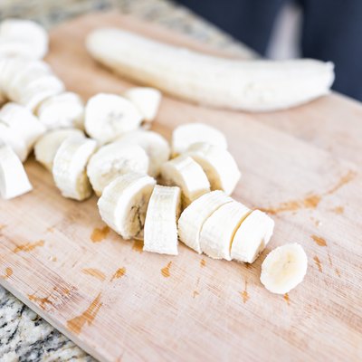 Chopped frozen banana on wooden bamboo chopping board closeup