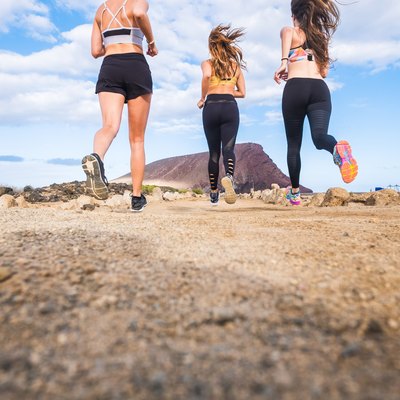 group of beautiful back view of females runners doing sport activity jogging in outdoor. mountain in background and enjoy the healthy leisure activity together. ground view and blue sky